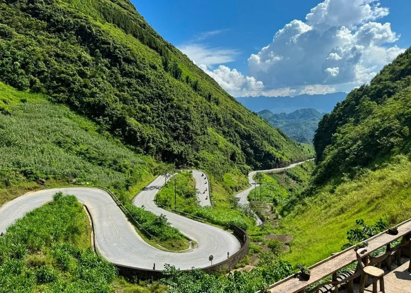 A winding switchback road cuts through green mountains on the Ha Giang Loop in Vietnam.