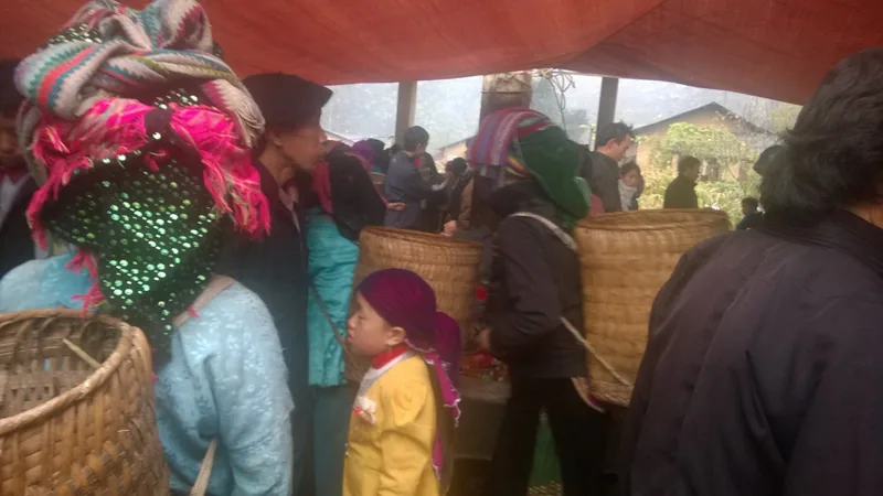Hmong women in colorful headscarves carry woven baskets through a crowded market in Ha Giang.