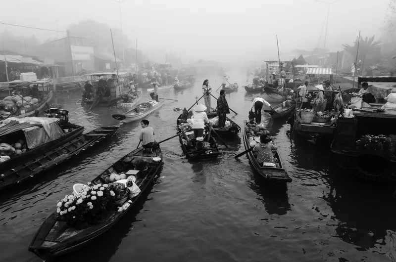 Wooden boats loaded with produce and flowers crowd the misty water at Nga Nam floating market in Soc Trang, Mekong Delta.