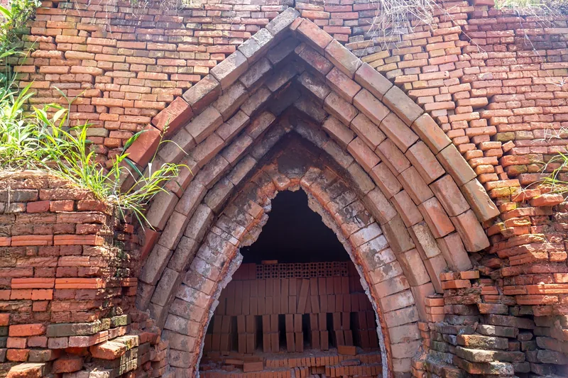 Pointed brick archway of a traditional kiln stacked with red bricks in the Mekong Delta.